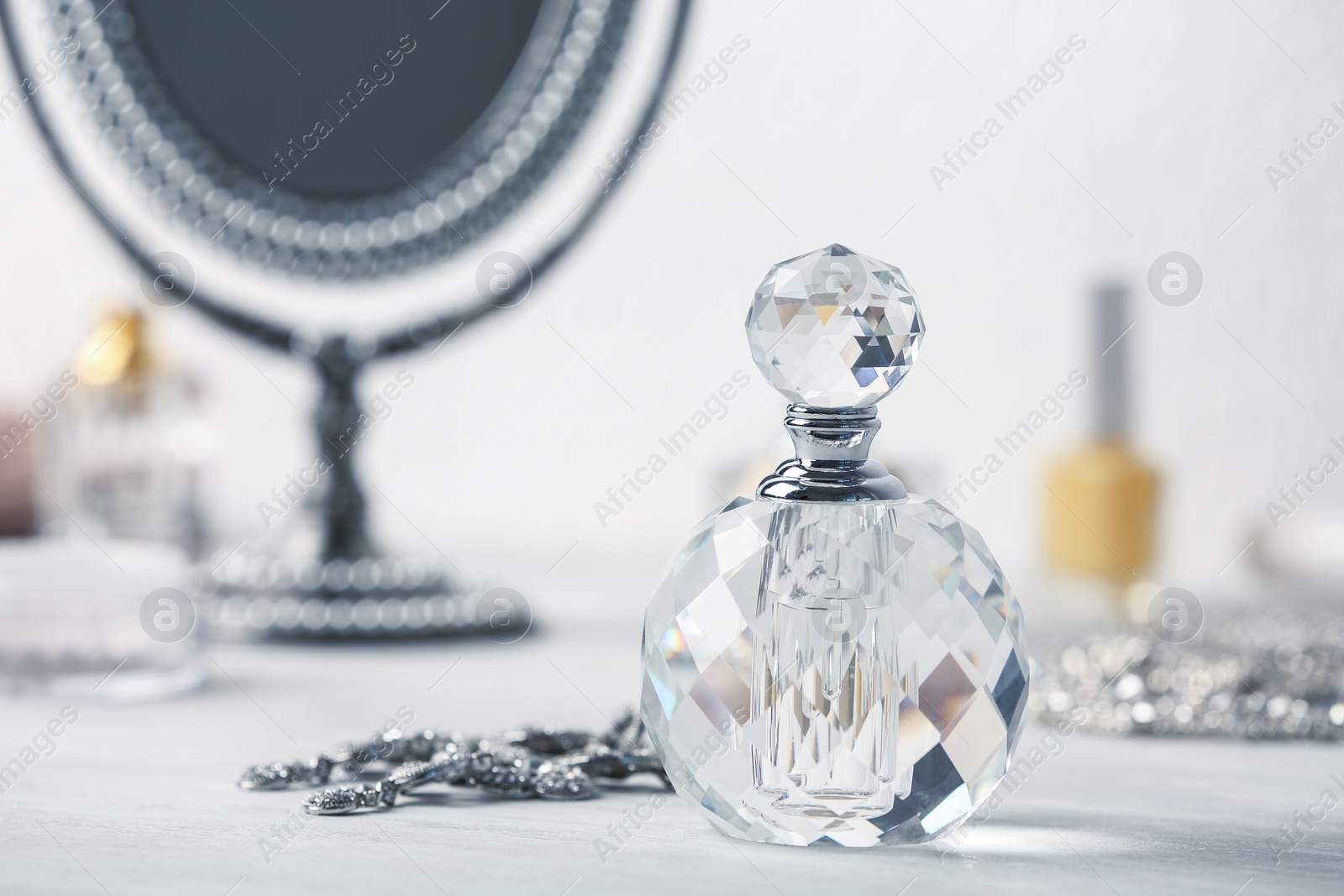 Photo of Perfume bottle and jewellery on dressing table. Space for text