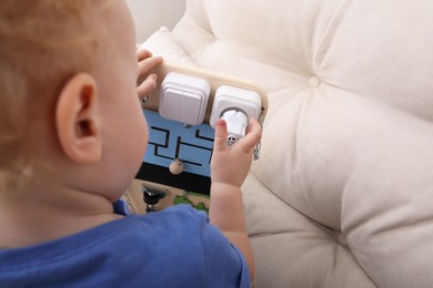 Photo of Cute little boy playing with busy board on sofa. Space for text