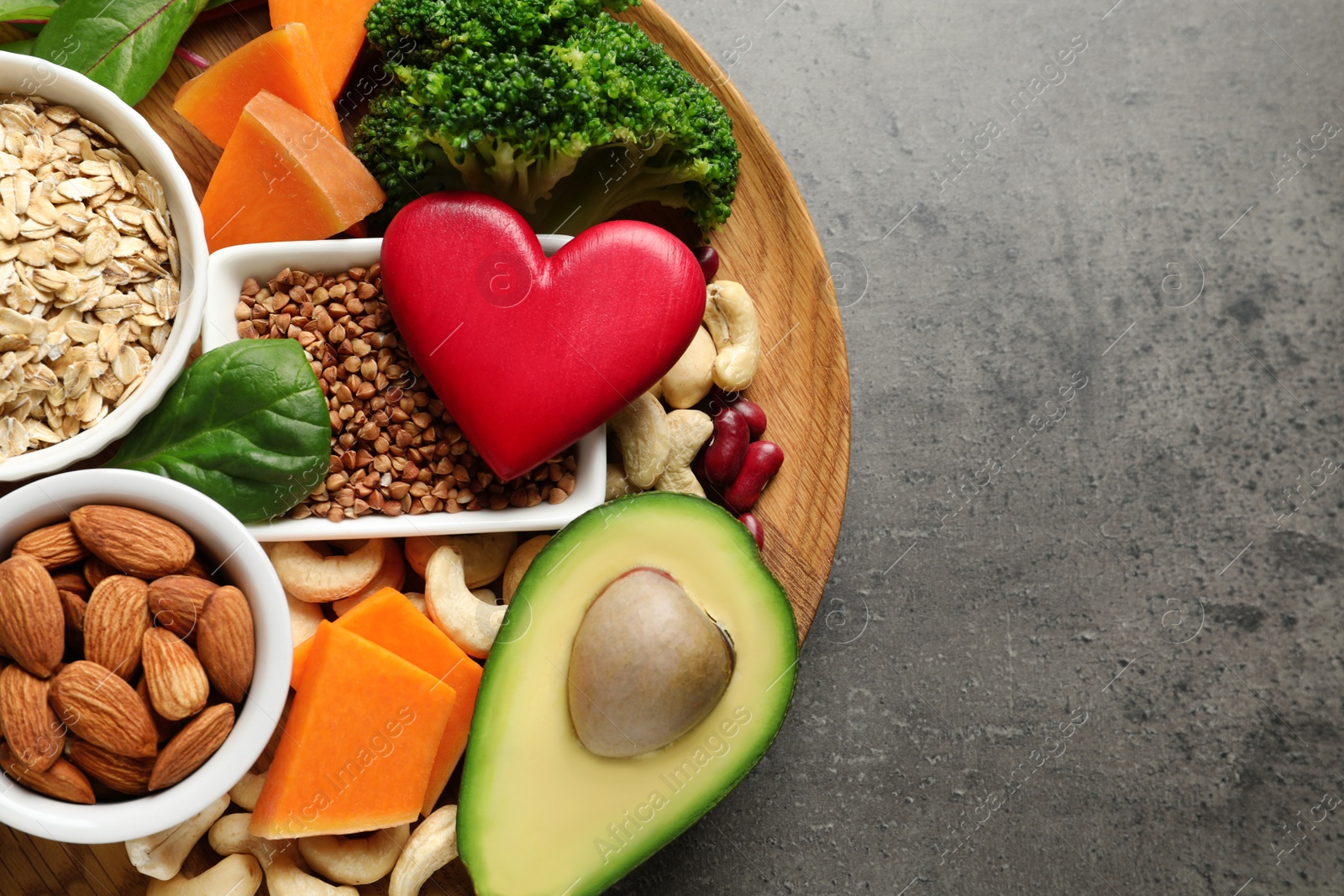 Photo of Wooden plate with heart-healthy products on grey background, top view. Space for text