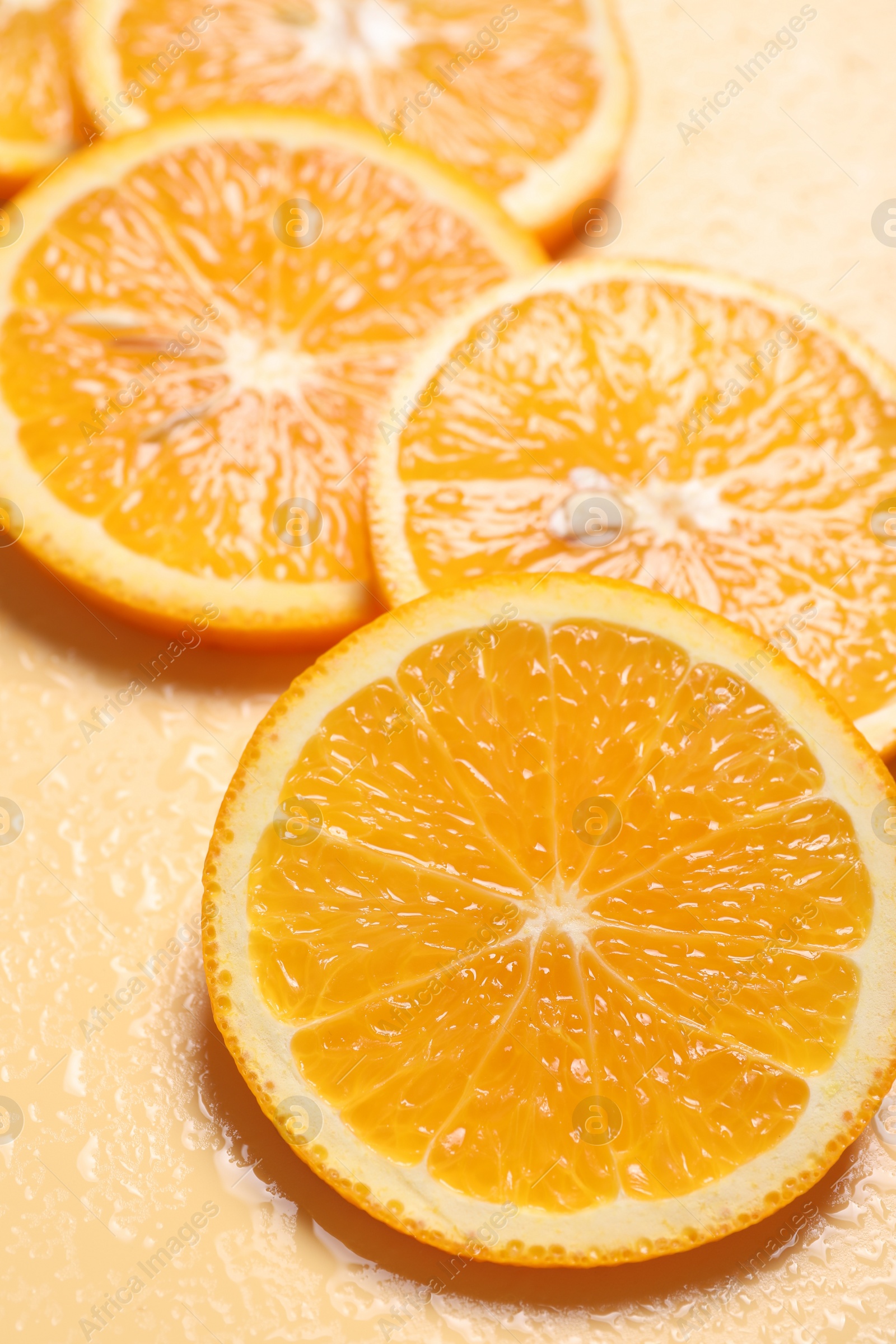 Photo of Slices of juicy orange and water on beige background, closeup