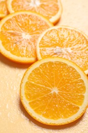 Slices of juicy orange and water on beige background, closeup