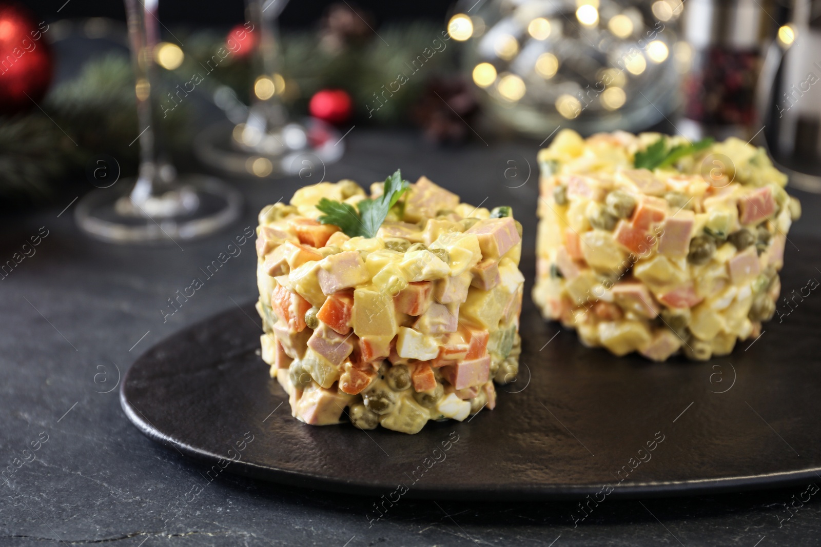Photo of Traditional russian salad Olivier served on black table, closeup