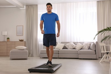 Photo of Sporty man training on walking treadmill at home