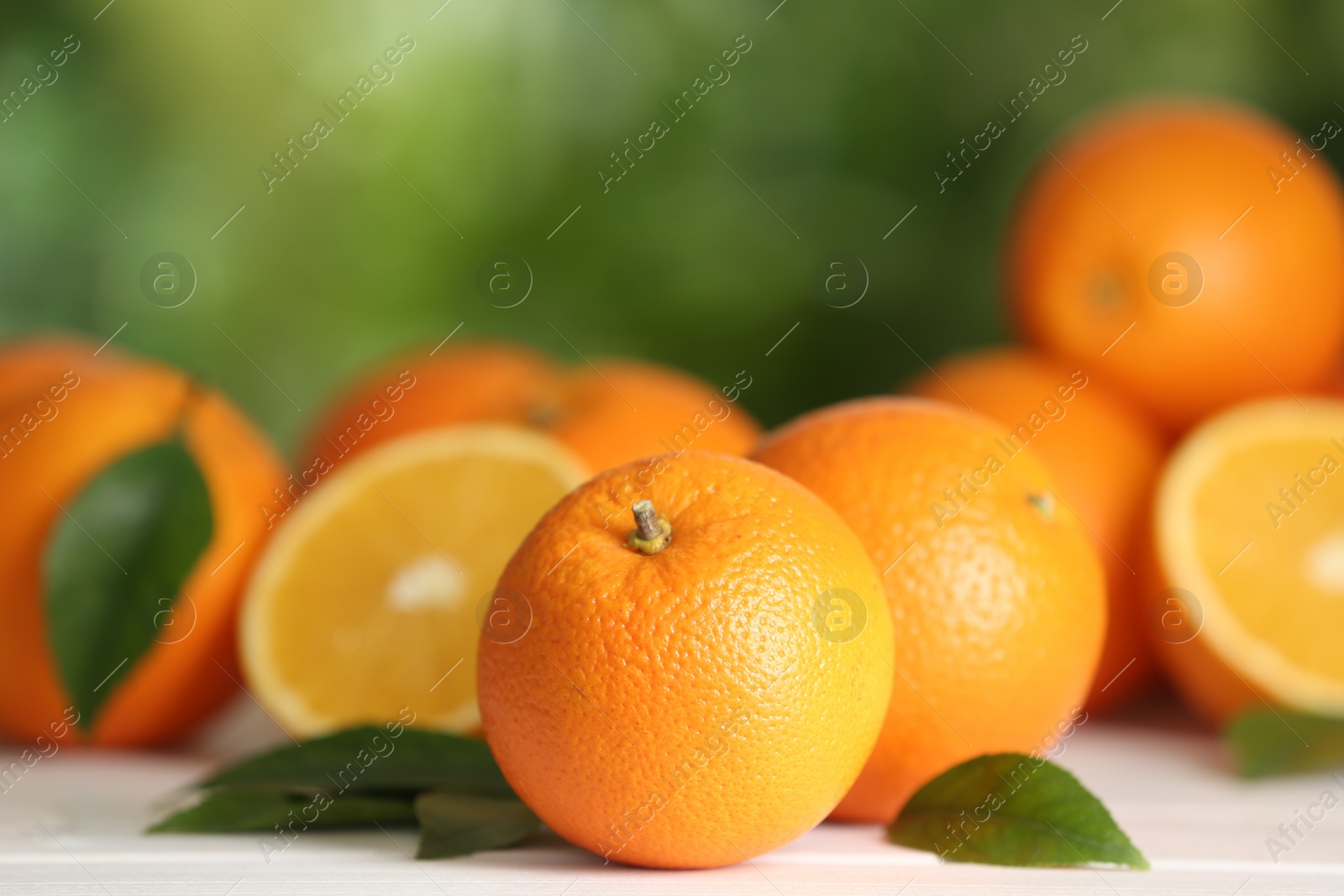 Photo of Fresh ripe oranges on white table against blurred background. Space for text