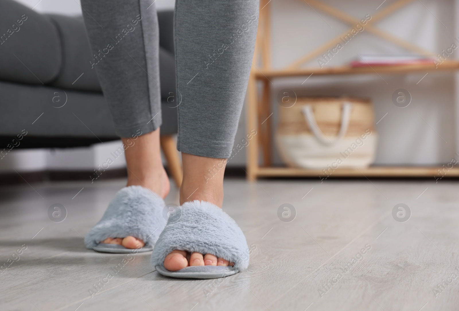 Photo of Woman wearing light blue soft slippers at home, closeup. Space for text