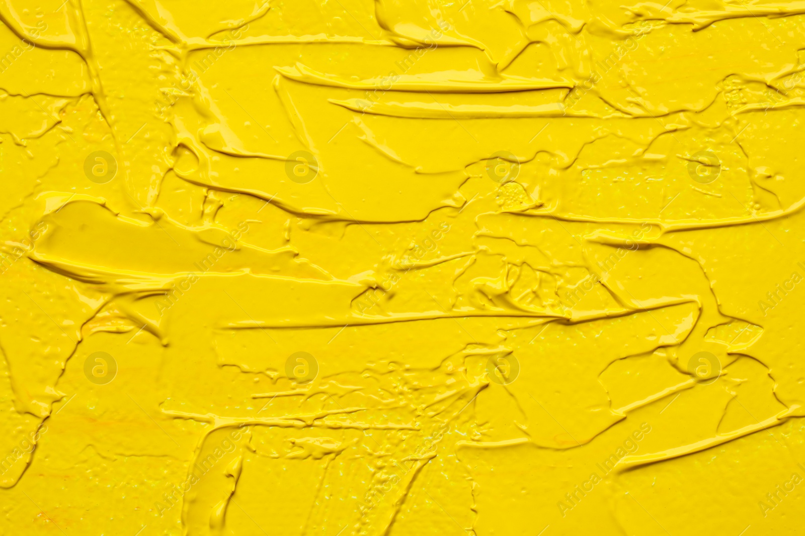 Photo of Beautiful strokes of yellow oil paint as background, closeup