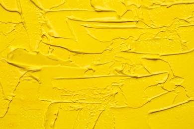 Photo of Beautiful strokes of yellow oil paint as background, closeup
