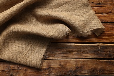 Burlap fabric on wooden table, top view