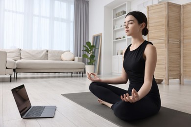 Beautiful girl having yoga class with online couch at home