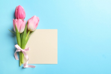 Beautiful spring tulips and card on color background, top view with space for text. International Women's Day