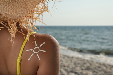 Young woman with sun protection cream on shoulder at beach, closeup