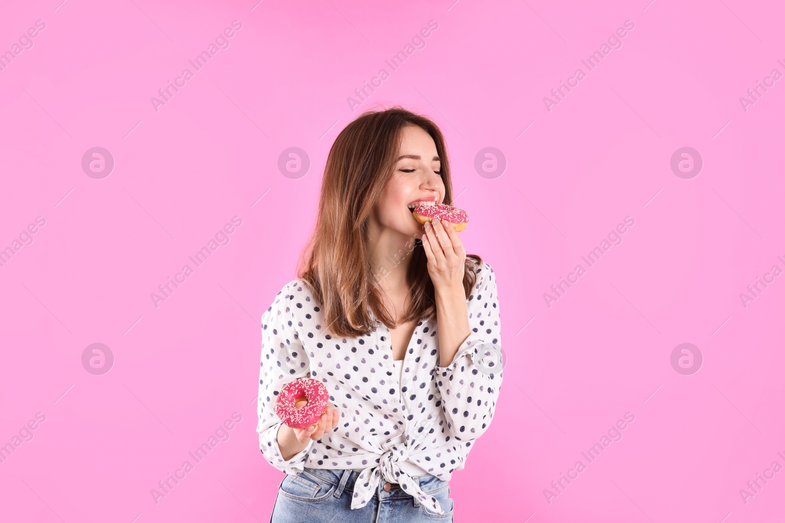 Photo of Beautiful young woman with donuts on light pink background