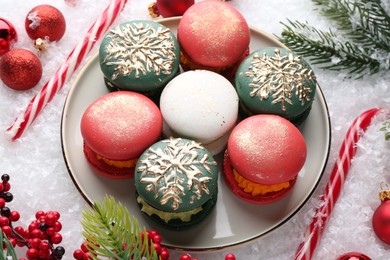 Photo of Beautifully decorated Christmas macarons, candy canes and festive decor on snow, above view