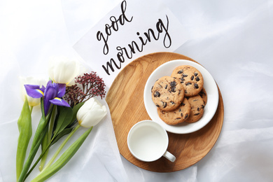 Photo of Delicious cookies, flowers and GOOD MORNING wish on white cloth, flat lay