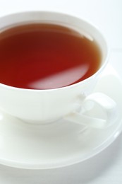 Photo of Aromatic tea in cup on white table, closeup