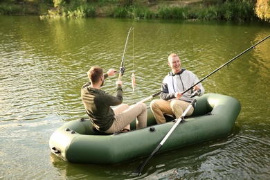 Photo of Friends fishing from boat on sunny day. Recreational activity