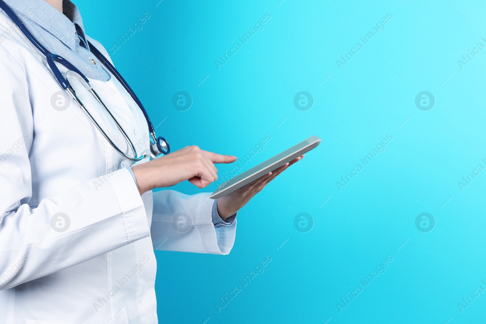 Photo of Female doctor holding modern tablet on color background, closeup with space for text