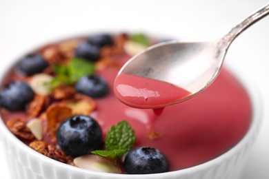 Photo of Delicious smoothie with fresh blueberries and granola on white background, closeup