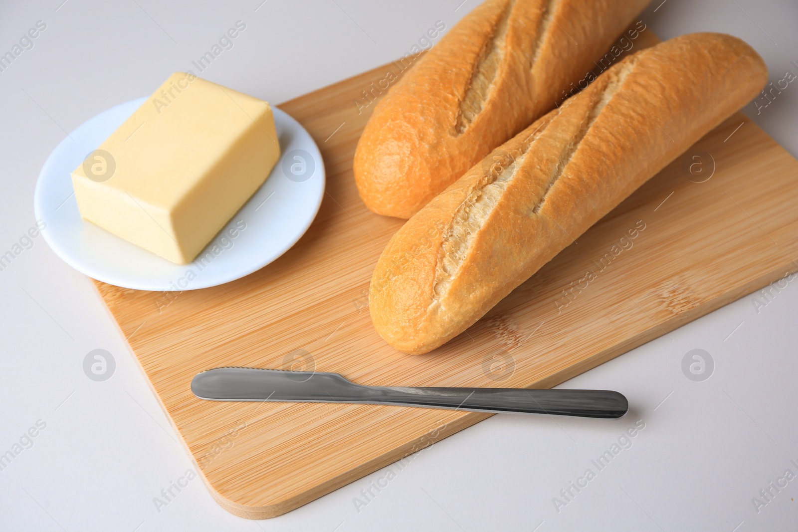 Photo of Tasty baguettes with fresh butter on white table