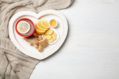 Heart shaped tray with lemon ginger tea on wooden background, flat lay. Space for text