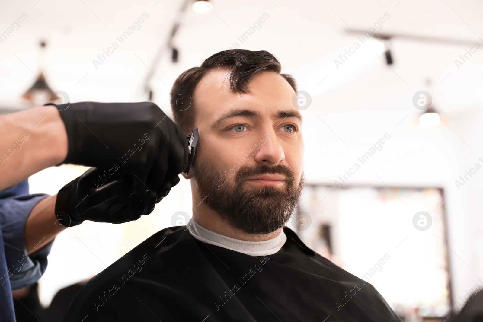 Photo of Professional barber working with client in hairdressing salon. Hipster fashion