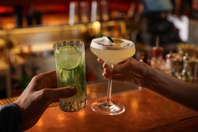 Photo of People holding glasses with fresh cocktails at bar counter, closeup