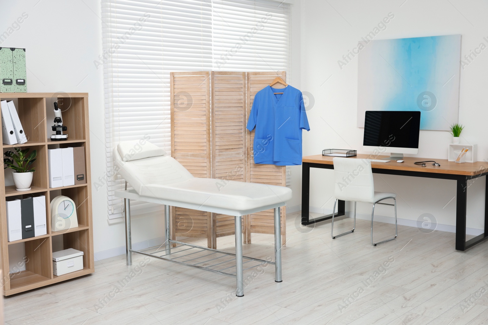 Photo of Modern medical office with doctor's workplace and examination table in clinic