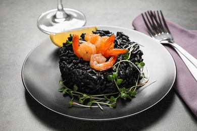 Delicious black risotto with shrimps on grey table