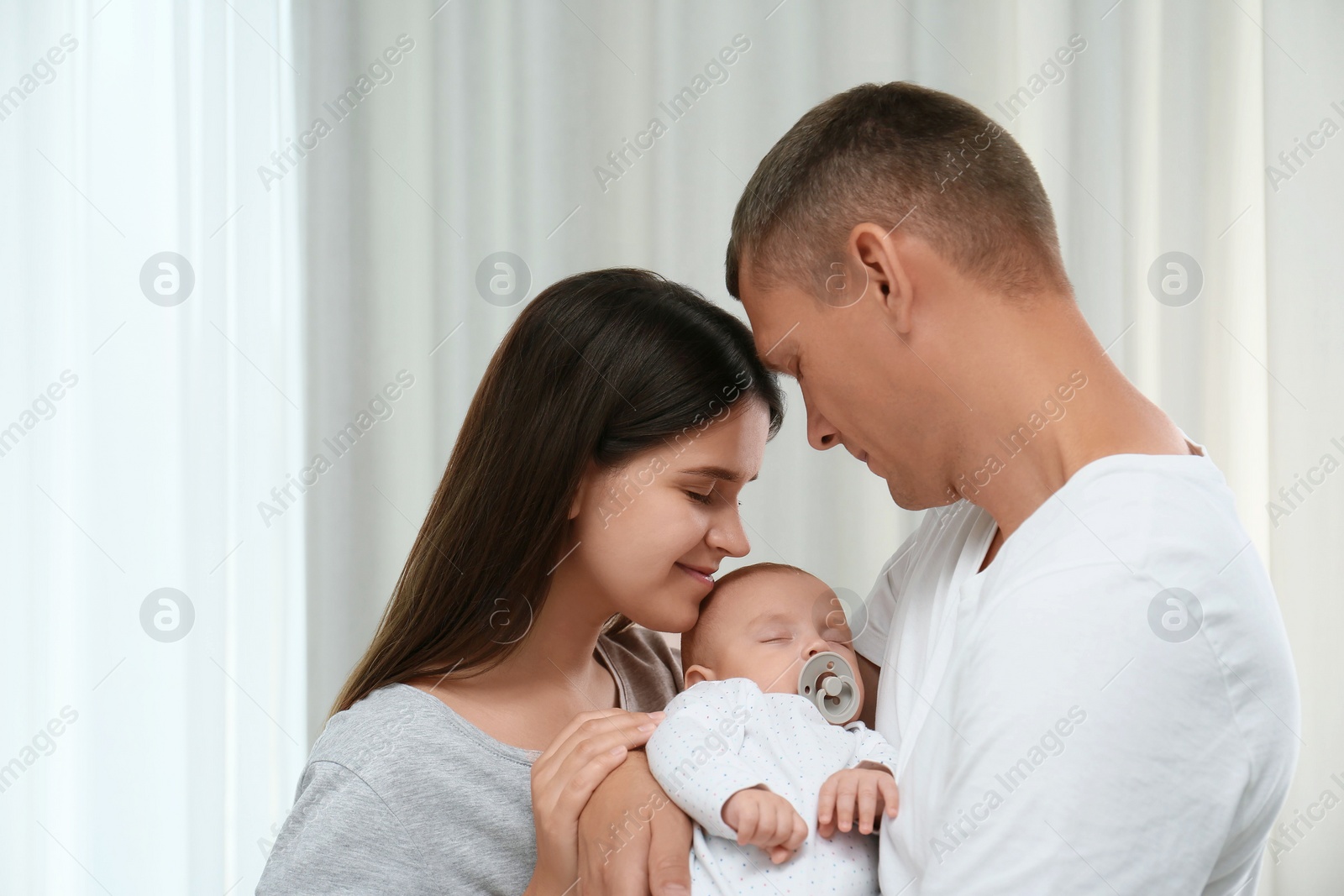 Photo of Happy family with their cute sleeping baby indoors