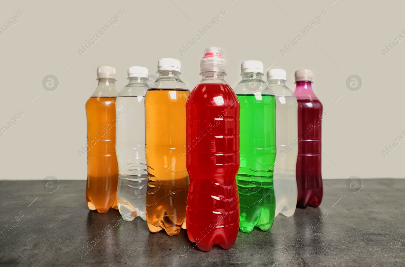 Photo of Bottles of soft drinks on table against grey background