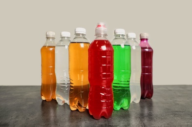 Photo of Bottles of soft drinks on table against grey background