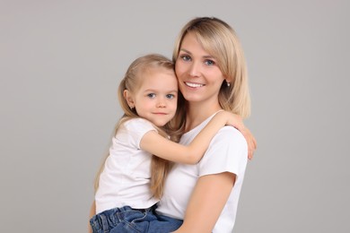 Family portrait of happy mother and daughter on grey background