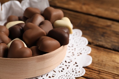 Photo of Delicious heart shaped chocolate candies on wooden table, closeup. Space for text