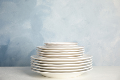 Photo of Stack of clean plates on table against light blue background. Space for text