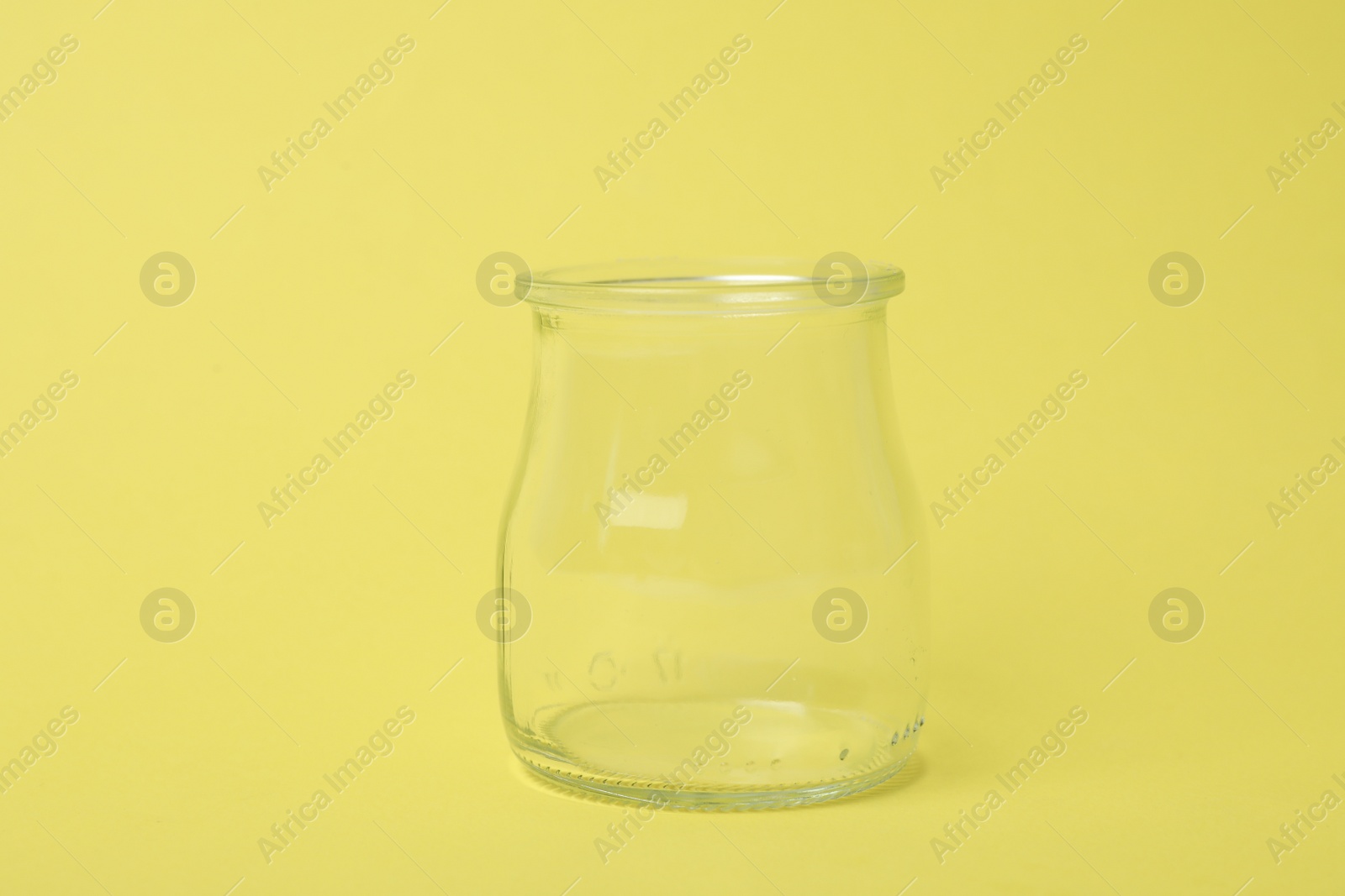 Photo of Open empty glass jar on light yellow background