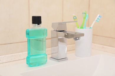 Mouthwash and holder with toothbrushes on sink in bathroom. Teeth and oral care