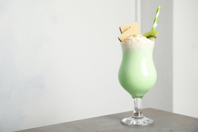 Glass with delicious milk shake on table against light background. Space for text