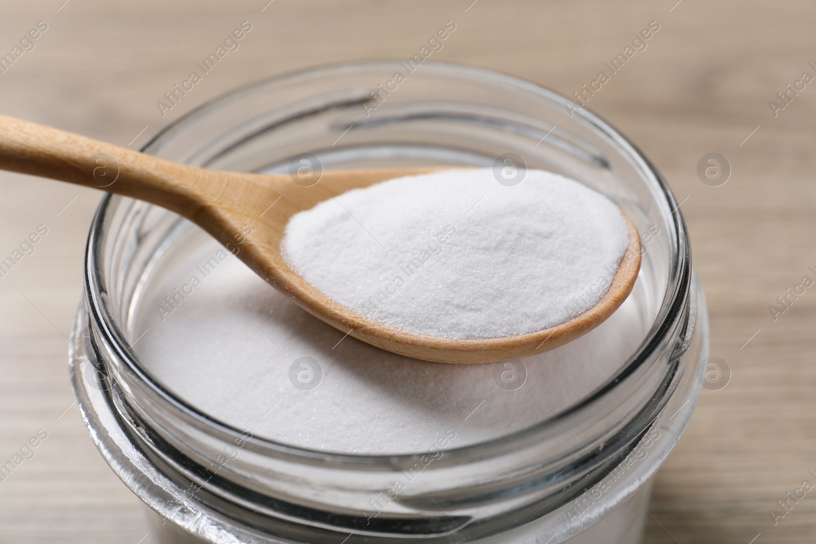 Photo of Baking soda in glass jar on wooden table, closeup