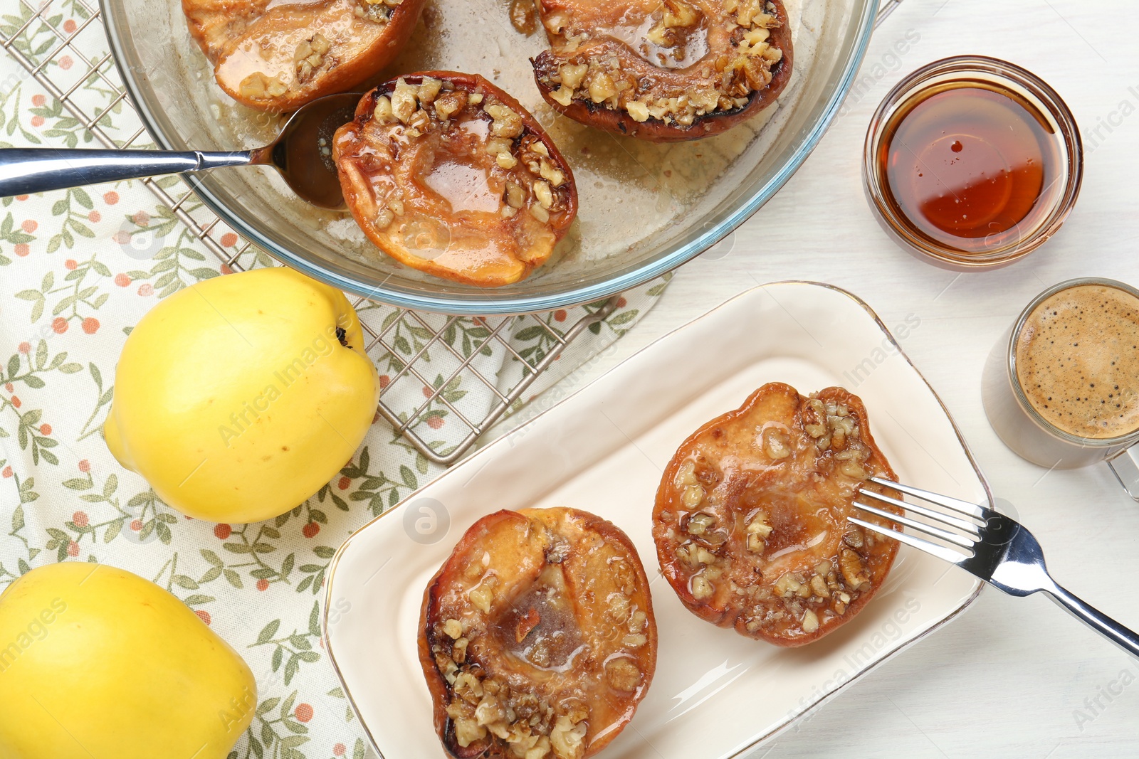 Photo of Delicious quinces baked with honey and walnuts on white wooden table, flat lay