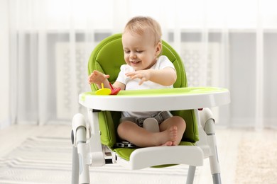 Photo of Children toys. Cute little boy playing with spinning tops in high chair at home