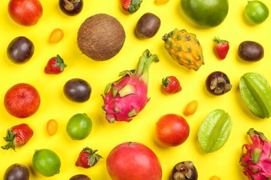 Assortment of fresh exotic fruits on yellow background, flat lay
