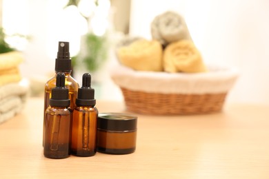 Photo of Bottles of essential oils and jar with cream on wooden table indoors, space for text. Spa time