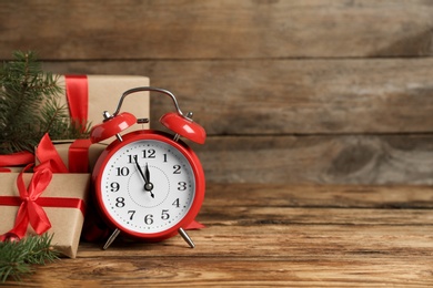 Christmas gifts and alarm clock on wooden table, space for text. Boxing day