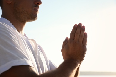 Photo of Man meditating against blue sky, closeup. Nature healing power