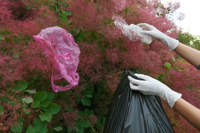 Photo of Woman with trash bag collecting garbage in park, closeup