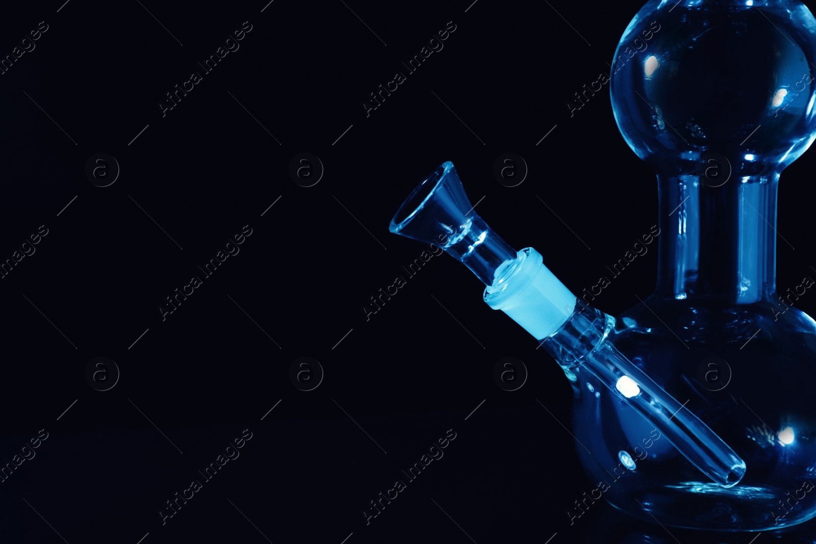 Photo of Closeup view of glass bong on black background, space for text. Smoking device