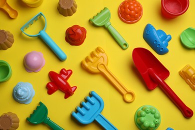 Beach sand toys on yellow background, flat lay