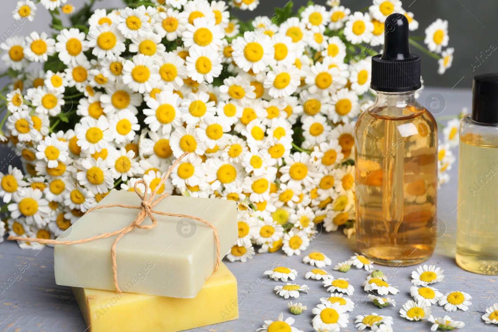 Photo of Composition with chamomile flowers and cosmetic products on wooden table