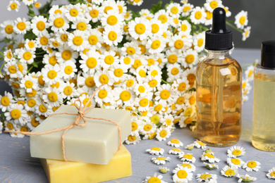 Composition with chamomile flowers and cosmetic products on wooden table