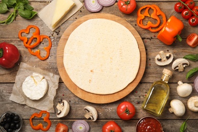 Photo of Flat lay composition pizza crust and fresh ingredients on wooden table